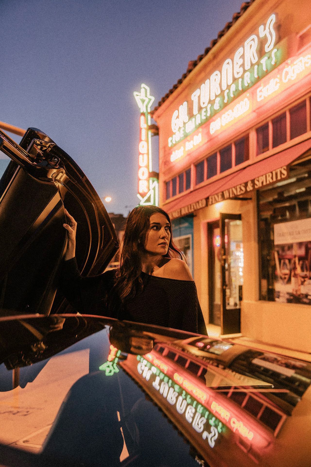 McLaren 720S – woman opening the butterfly door under the neon signs of a Los Angeles liquor store at dusk, photo Jon Filin