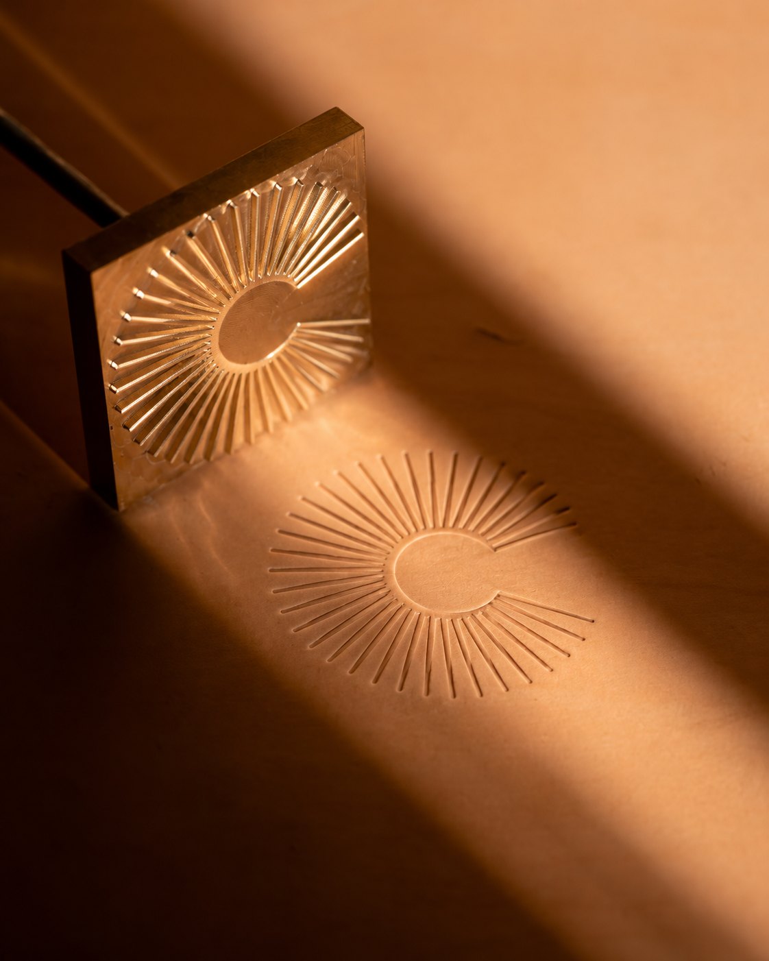 Optique Carnot – brass stamp of the sun monogram and its imprint on paper, branding by Jon Filin